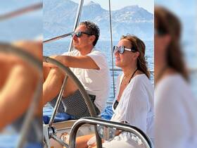 A couple enjoys a serene sailing experience, surrounded by stunning mountain views and the calm ocean — perfect for romantic getaways or adventure on the water.