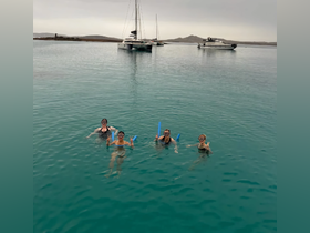 A group of friends enjoys snorkeling in crystal-clear waters, showcasing a fun day on the water with boats anchored in the background.