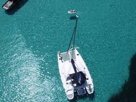 Aerial view of a catamaran cruising through crystal-clear waters, showcasing the beauty of the vessel against a stunning turquoise backdrop.