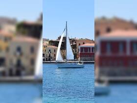 A beautiful sailboat glides through clear waters, showcasing its elegant sails against a picturesque backdrop of colorful buildings.