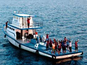 A lively group celebrates aboard a boat in the ocean, showcasing the joy of shared experiences on the water.