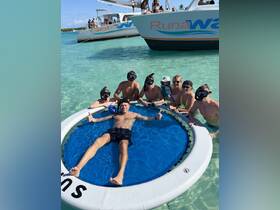 A lively group enjoys a fun day of snorkeling and swimming in shallow waters, with catamarans in the background, creating a perfect atmosphere for adventure and relaxation.