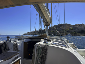 A view from the helm of a sailboat, showcasing the interior space and the scenic backdrop of a coastal town, perfect for sailing enthusiasts.