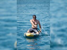 A man enjoys paddleboarding in clear blue waters, showcasing the thrill of water sports and outdoor adventures.