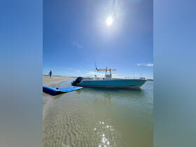 A sleek Century boat is docked on a sandy shore under a bright sun, showcasing the perfect setting for a day on the water.