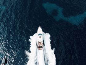 A stunning aerial view of a sleek yacht cruising through deep blue waters, showcasing the beauty of boating adventures on the open sea.