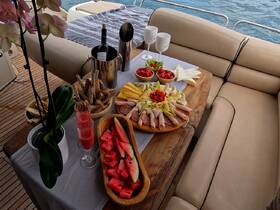 An inviting spread of charcuterie, fresh fruits, and cocktails set up on a boat, perfect for enjoying a relaxing day on the water.
