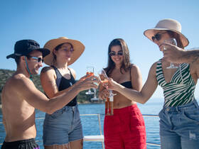 A lively group toasts with cocktails aboard a yacht, enjoying a sunny day on the water — perfect for celebrations and memorable gatherings.