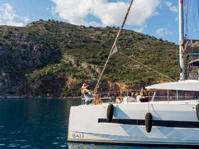 Guests relax aboard a Bali catamaran, enjoying the stunning views of the surrounding landscape — a perfect setting for a memorable sailing experience.