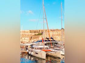 A stunning catamaran docked in a picturesque harbor, showcasing its sleek design against a backdrop of historic architecture.