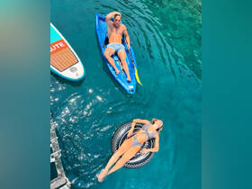 A couple enjoys a sunny day on the water, with one kayaking and the other relaxing on a float — perfect for summer adventures and water fun.