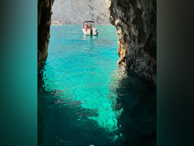 A scenic view from a cave entrance showcasing a boat with guests enjoying the turquoise waters — a perfect spot for swimming and exploration.