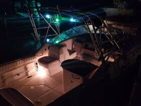 A nighttime view of the interior of a boat, showcasing the seating and helm area illuminated by soft lighting, perfect for evening outings on the water.