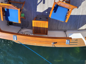 An aerial view of the seating area on a boat, featuring wooden chairs with blue cushions, perfect for relaxing while enjoying the water.