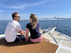 A couple enjoys a serene moment on the deck of a boat, soaking in the sun and ocean views — perfect for romantic getaways or relaxing cruises.