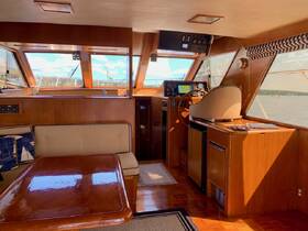 Interior view of a well-appointed boat cabin featuring a helm, seating area, and large windows offering scenic views — ideal for comfortable cruising.