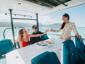 A joyful group toasts with cocktails aboard a stylish boat, surrounded by stunning scenery — perfect for memorable celebrations on the water.