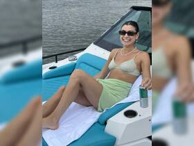 A woman relaxes on the deck of a boat, enjoying a drink and soaking up the sun — perfect for a day of leisure on the water.
