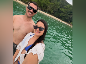 A couple enjoys a sunny day at the beach, capturing a joyful selfie in the clear waters — perfect for romantic getaways and beach adventures.