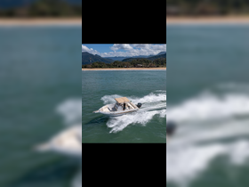 A sleek speedboat named 'Safira' glides through the water, showcasing its dynamic design against a backdrop of lush mountains and a sandy shoreline.