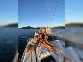 A lively group enjoys a sailing adventure, capturing a fun moment on the deck of a catamaran with stunning coastal views in the background.