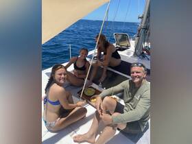 A cheerful group enjoys snacks aboard a sailboat, capturing the essence of a fun day on the water with friends and family.