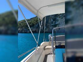 A view of the helm area inside a boat, showcasing the console and seating against a backdrop of stunning turquoise waters and rocky cliffs.