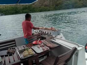 A chef prepares a delicious barbecue on a boat, showcasing an array of fresh ingredients and grilling equipment — perfect for onboard dining experiences.