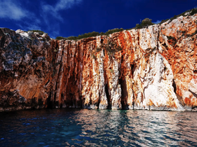 Stunning view of vibrant cliffs rising above the calm ocean waters, showcasing the natural beauty of the coastline — perfect for scenic boat tours.