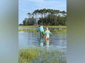 A group of individuals enjoys a fishing adventure in shallow waters, showcasing the thrill of casting nets in a scenic outdoor setting.