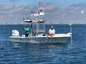 Two anglers enjoy a day of fishing aboard the 'White Lines' boat, showcasing the perfect outdoor adventure on the water.