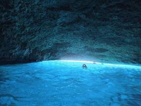 Swimmers explore the stunning underwater cave, illuminated by natural light, creating a mesmerizing blue ambiance — a perfect highlight of an adventurous trip.