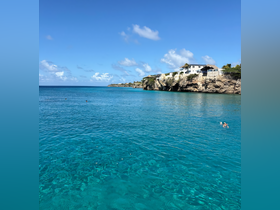 A stunning view of crystal-clear waters with swimmers enjoying the beautiful coastline — a perfect destination for water activities and relaxation.