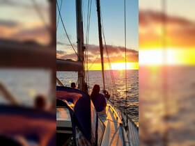 A serene sunset view from a sailing yacht, with guests enjoying the picturesque moment — perfect for romantic getaways or sunset cruises.
