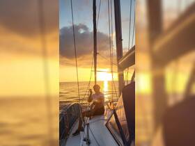 A person enjoys a serene sunset while relaxing on the deck of a sailboat, capturing the essence of peaceful sailing experiences.