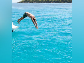 A person leaps into the vibrant turquoise waters, capturing the thrill of summer fun and adventure on the water.