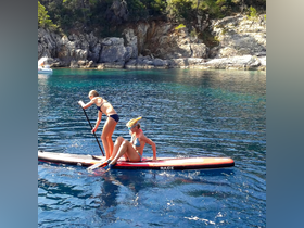 Two girls enjoy paddleboarding in crystal-clear waters, showcasing a fun day of water activities and adventure in a beautiful natural setting.