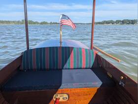 A cozy seating area inside a boat, featuring a striped cushion and an American flag, perfect for relaxing while enjoying the water views.