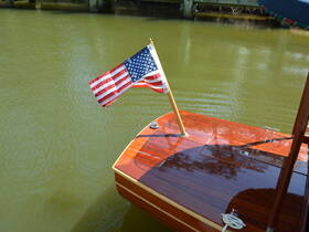 A beautifully crafted wooden boat with an American flag waving, docked in calm waters — perfect for showcasing classic boating craftsmanship.