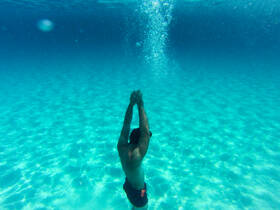 A swimmer dives into the crystal-clear waters, showcasing the beauty of underwater adventures — perfect for snorkeling or diving enthusiasts.