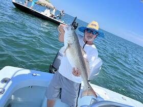 A proud angler holds up a large fish while enjoying a day of fishing on the water, showcasing the thrill of outdoor adventures.