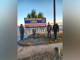 A group of friends proudly displays their catch at Conn Brown Harbor in Aransas Pass, Texas, celebrating a successful fishing trip.