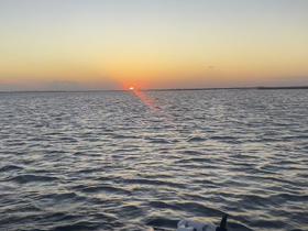 A serene sunset over calm waters, showcasing the beauty of nature from a boat's perspective — perfect for tranquil evening cruises.