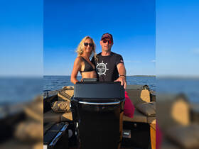 A couple enjoys a sunny day on the water, posing together at the helm of their boat — perfect for romantic outings or fun adventures on the sea.