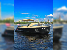 A sleek black boat glides through calm waters, showcasing its elegant design against a vibrant blue sky — perfect for leisurely outings or sightseeing tours.