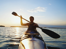A kayaker paddles through shimmering waters at sunset, capturing the essence of adventure and tranquility on the water.