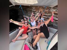 A lively group of friends celebrates aboard a boat, showcasing joy and camaraderie against a stunning rocky backdrop — perfect for unforgettable adventures on the water.