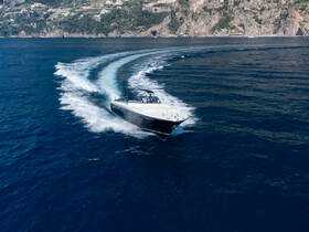 A stunning aerial view of a sleek speedboat cutting through the deep blue waters, showcasing the thrill of boating along the picturesque coastline.