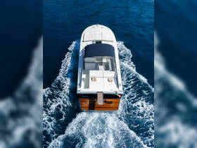 Aerial view of a sleek yacht cruising through deep blue waters, showcasing its elegant design and spacious deck.