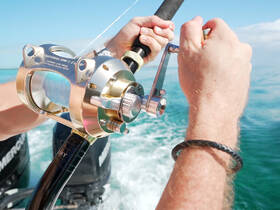 A close-up of hands gripping a fishing reel, highlighting the excitement of fishing on the water — perfect for adventure seekers and fishing enthusiasts.